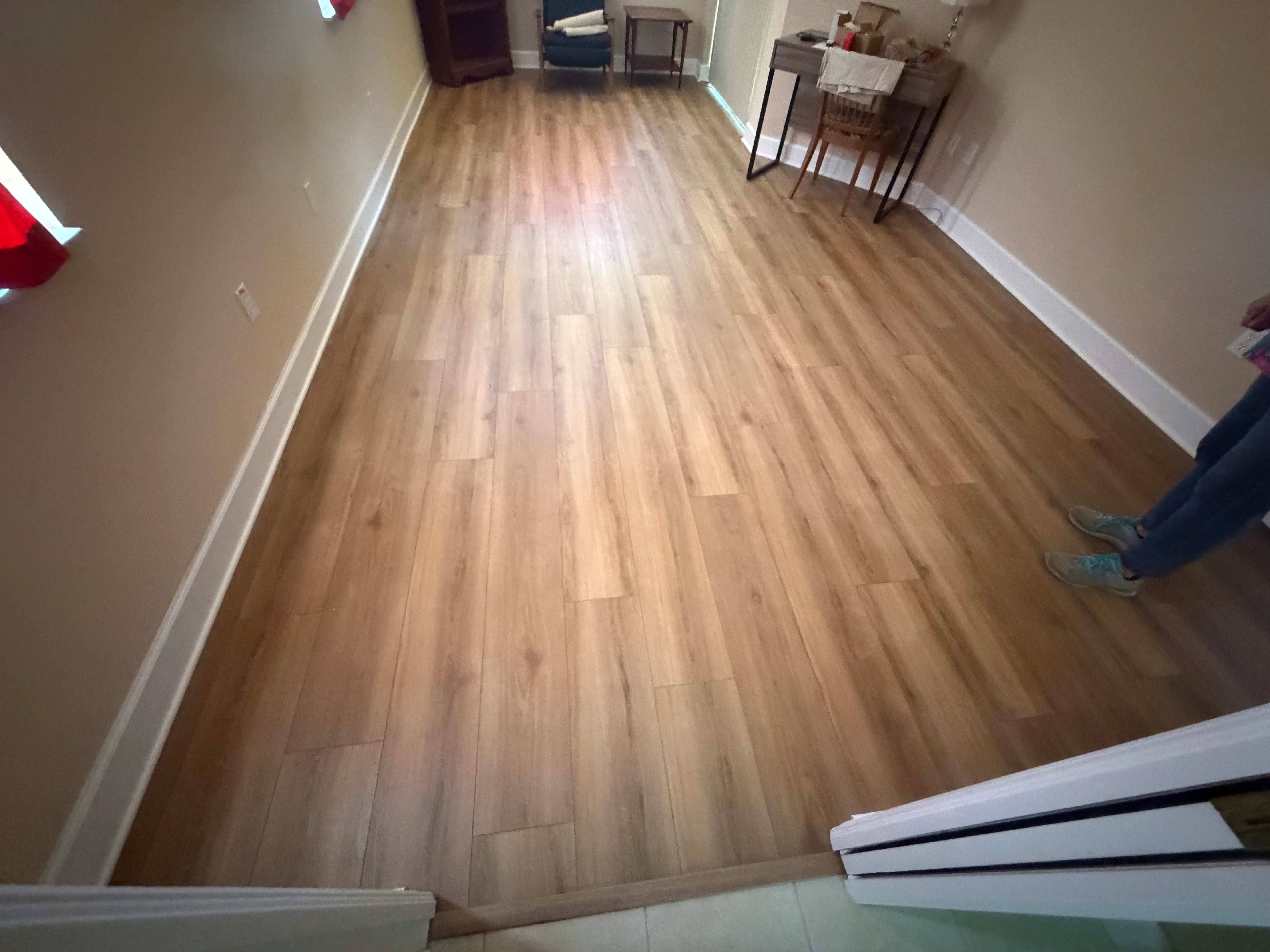 Light wood-tone laminate flooring with white baseboards in residential room