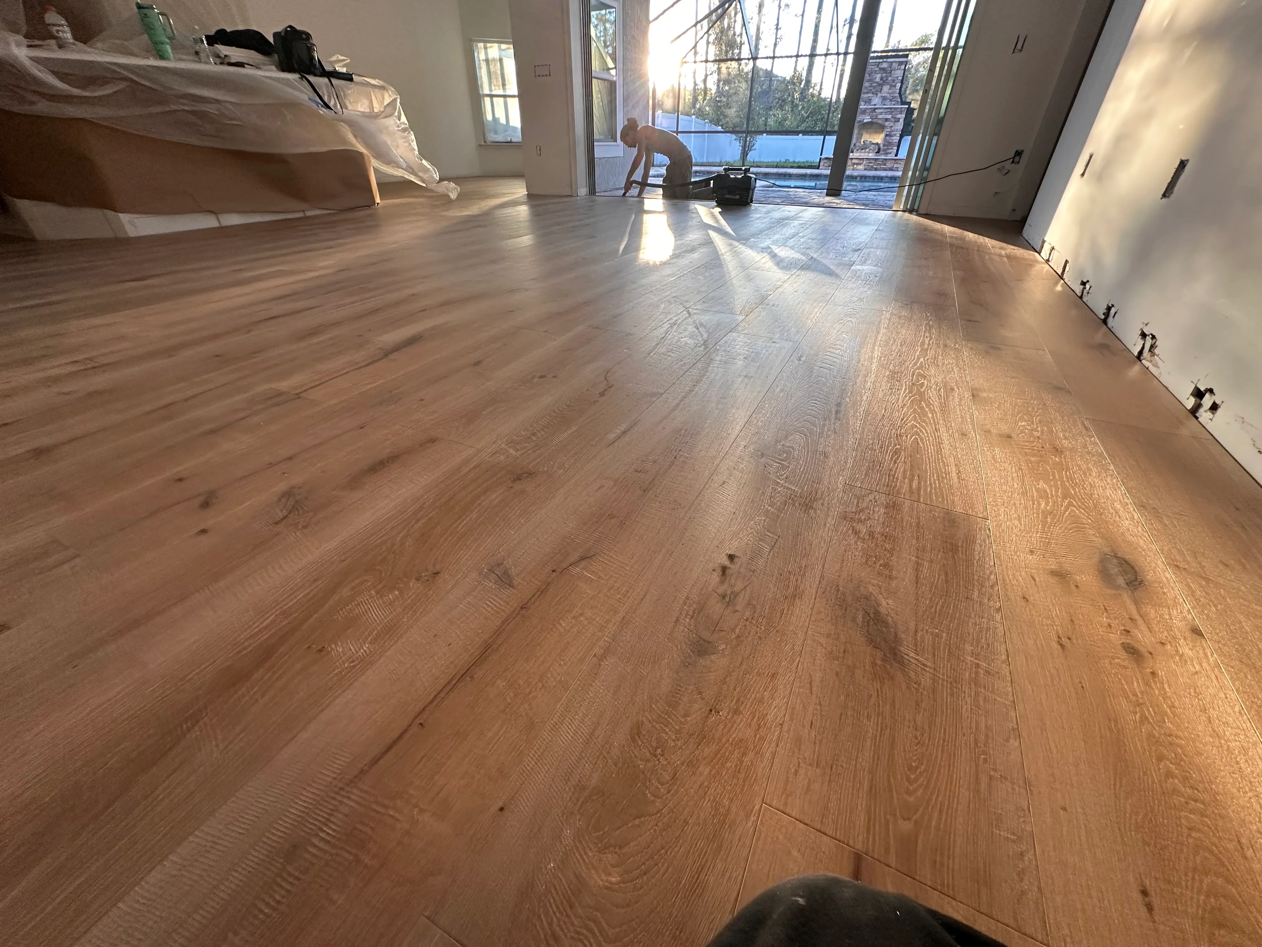 Wide-plank engineered wood flooring with natural oak finish and baseboard trim in open living area