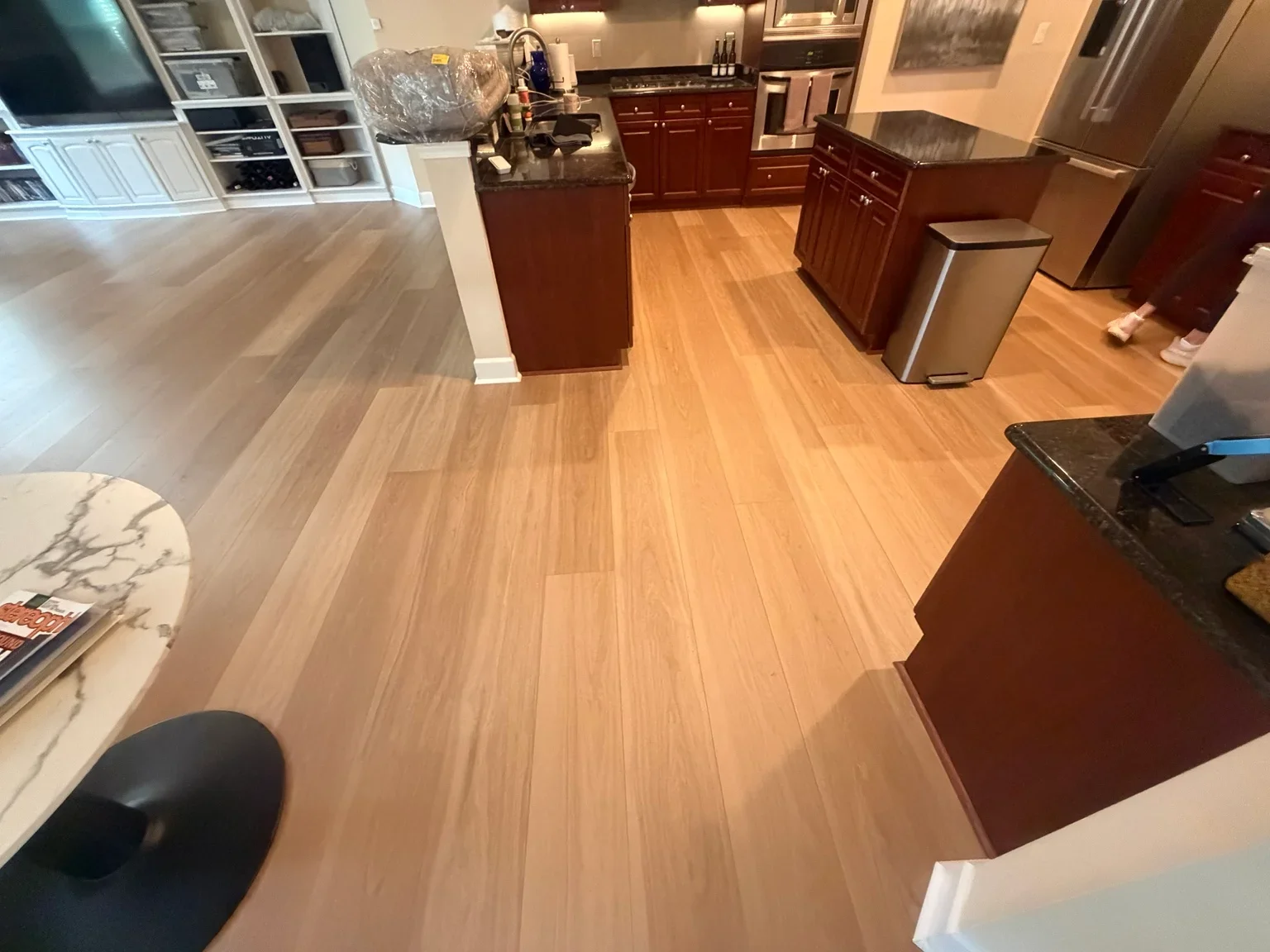 Warm wood-tone laminate flooring installed in kitchen with cherry cabinets and stainless steel appliances
