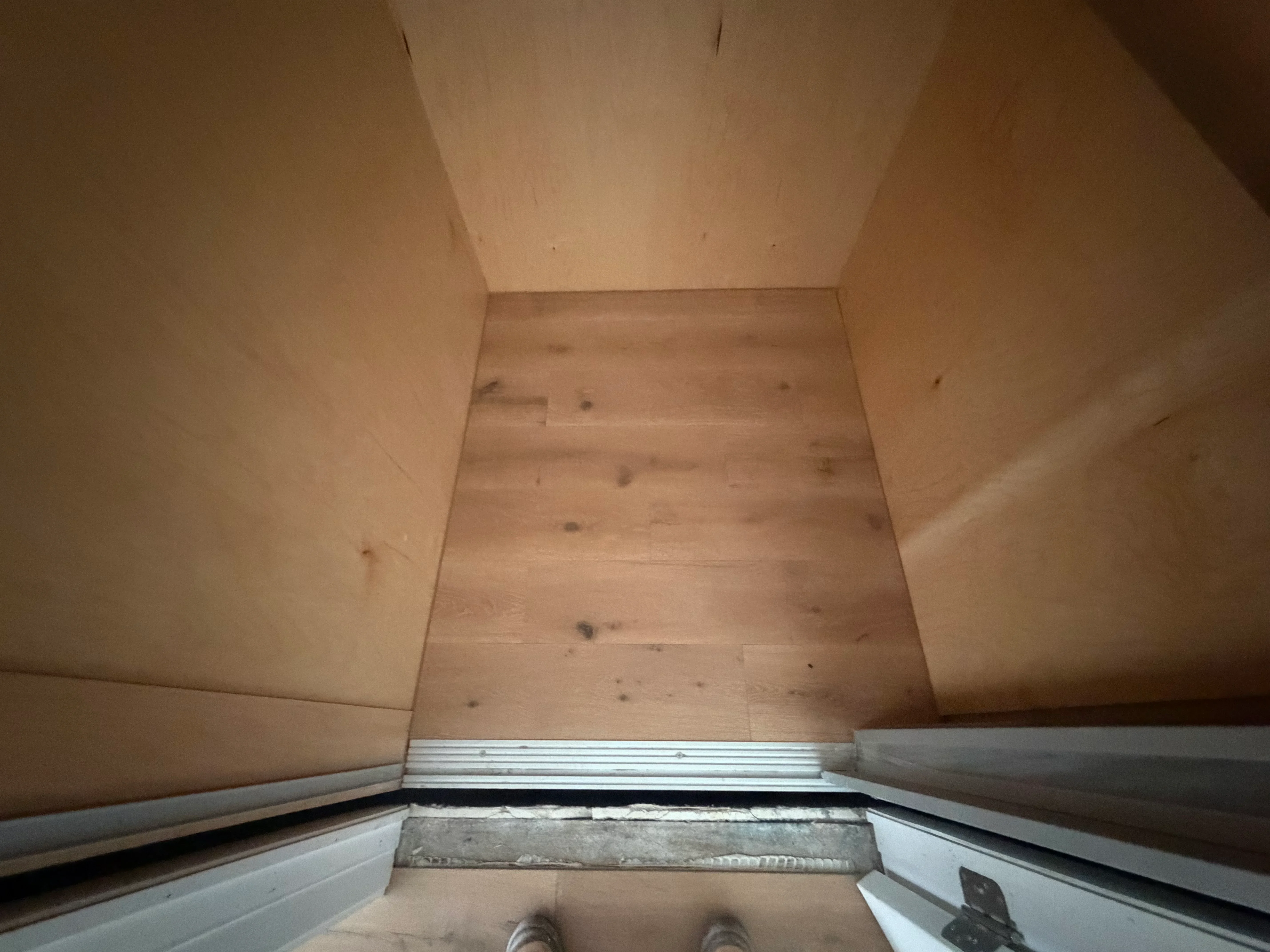 Light hardwood flooring installation with metal transition trim at doorway threshold