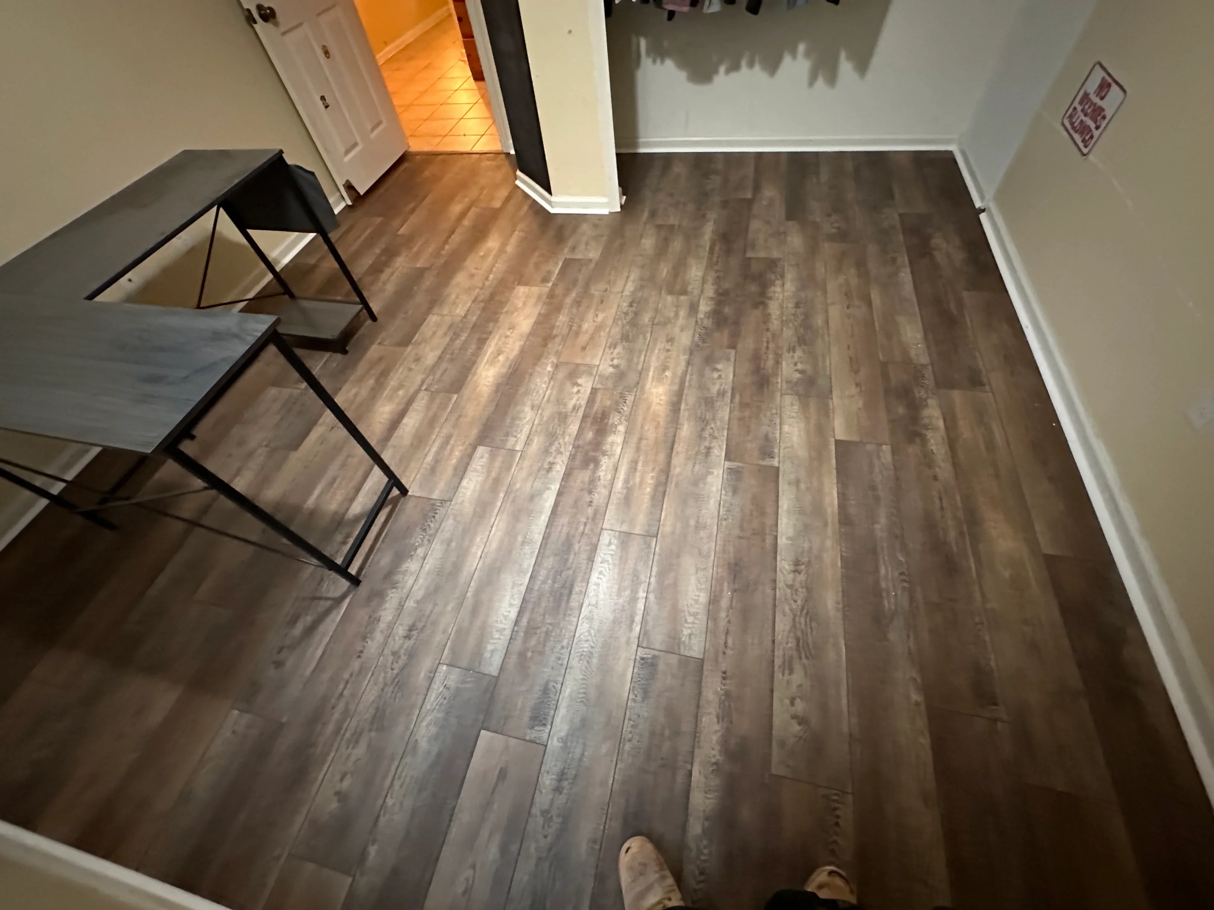 Luxury vinyl plank flooring in wood-grain brown tones installed in staggered pattern with white baseboards