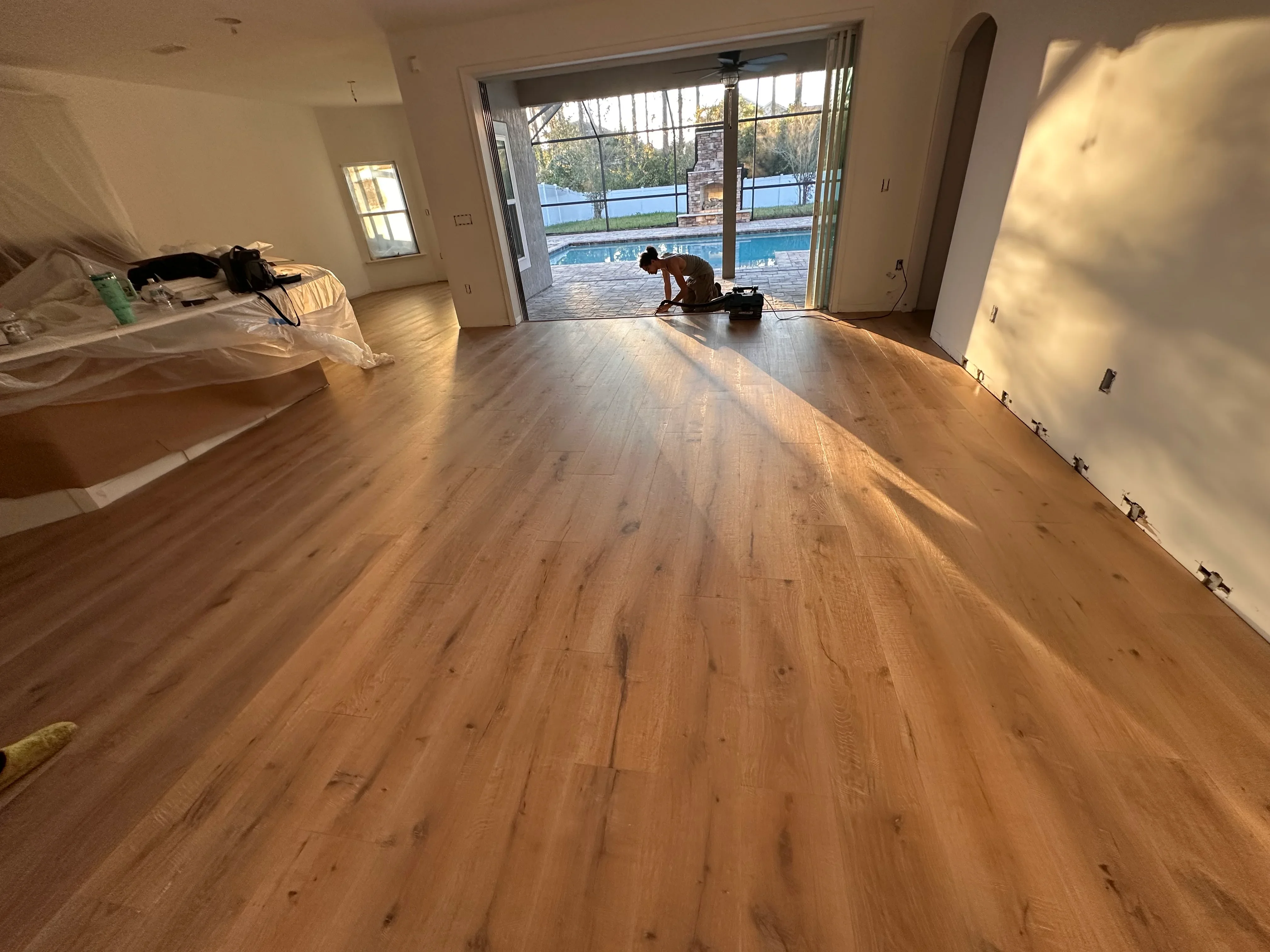 Wide-plank luxury vinyl flooring installation in open room with sliding glass doors