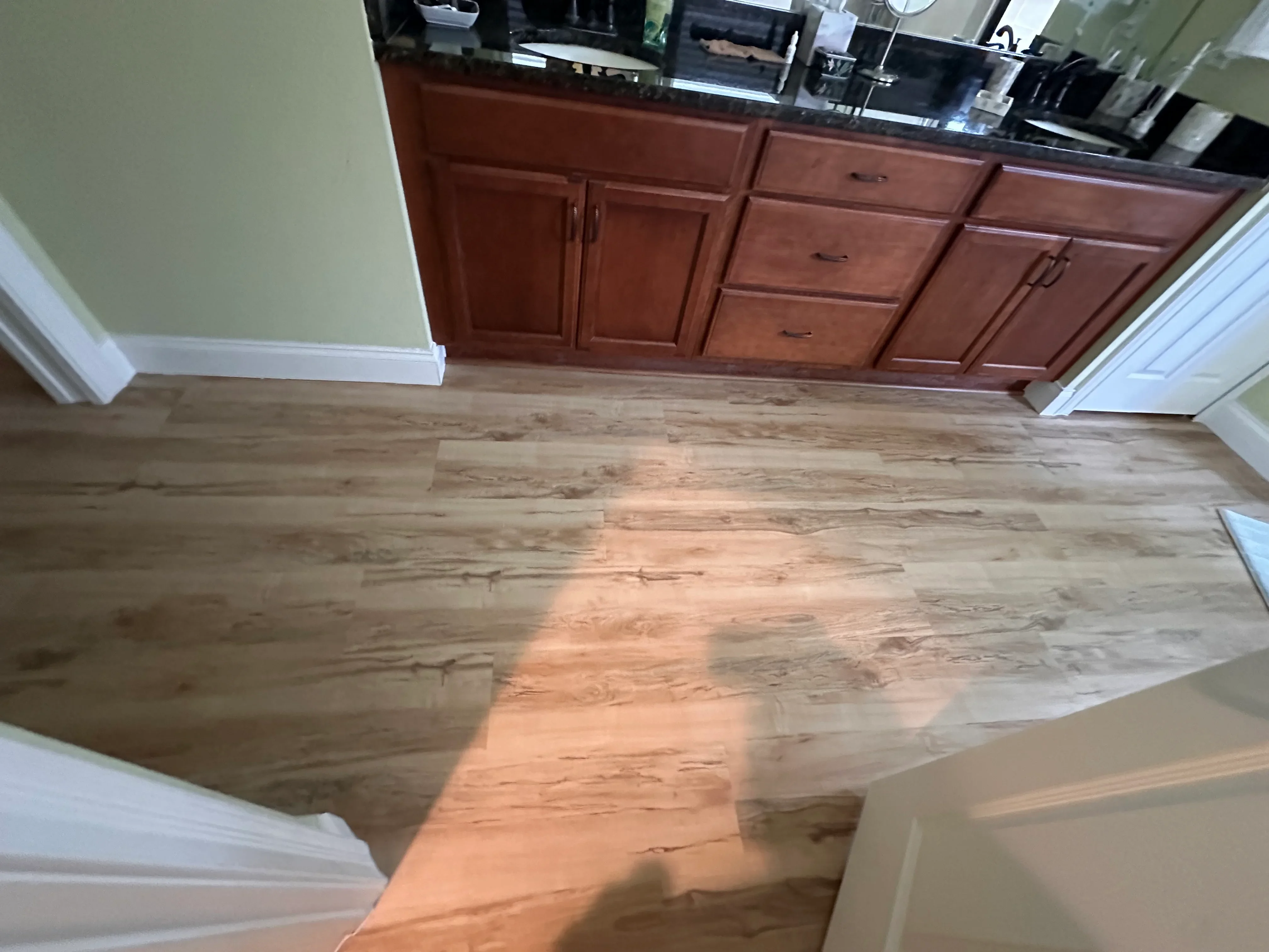 Luxury vinyl plank flooring with wood-grain finish installed in kitchen with cherry cabinets