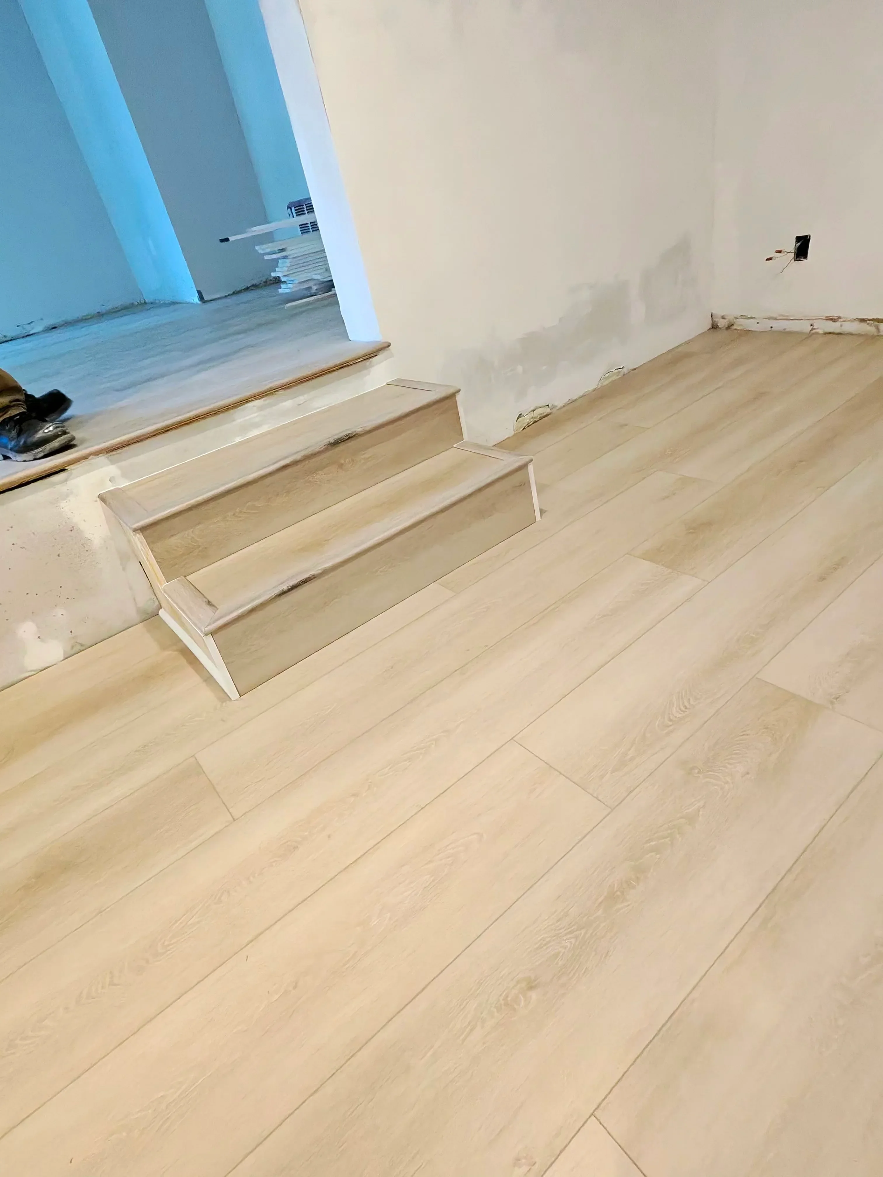 Light oak wood plank flooring with custom wooden transition strips at floor level changes