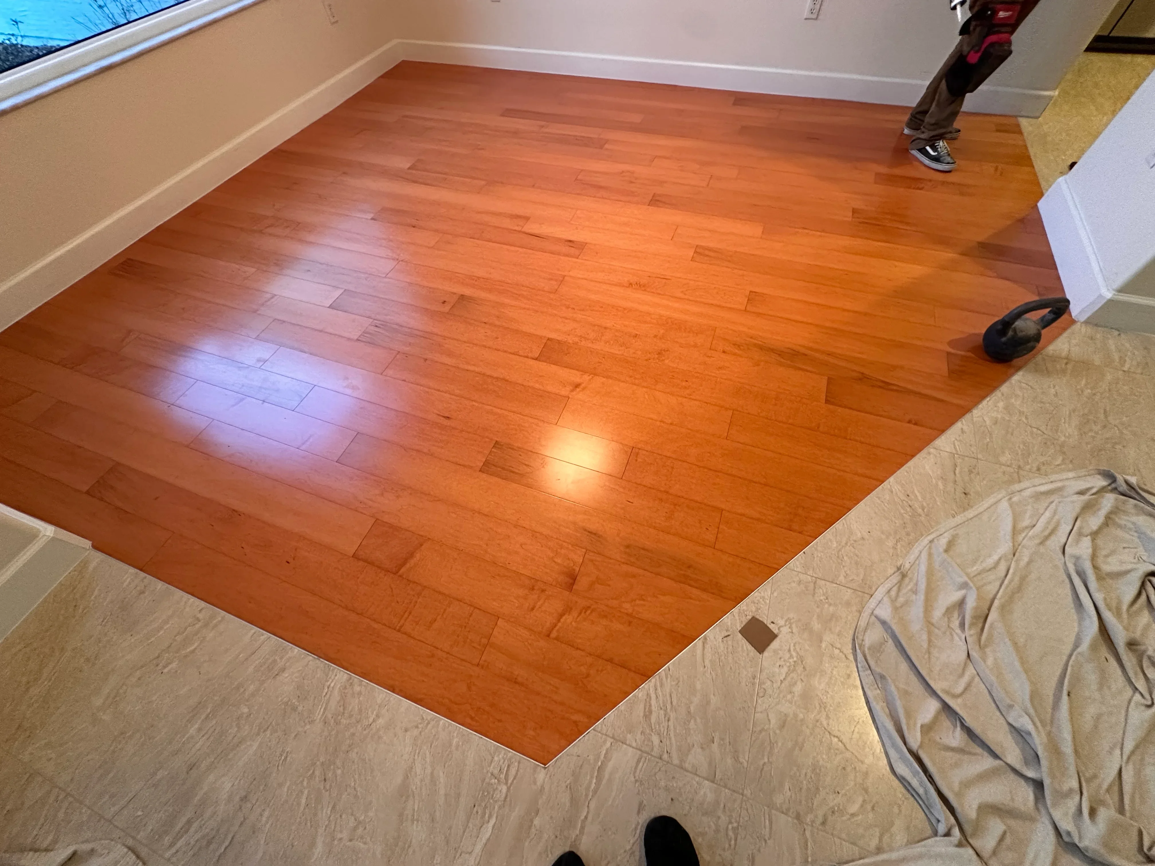 Newly installed cherry hardwood flooring with plank pattern and white baseboards