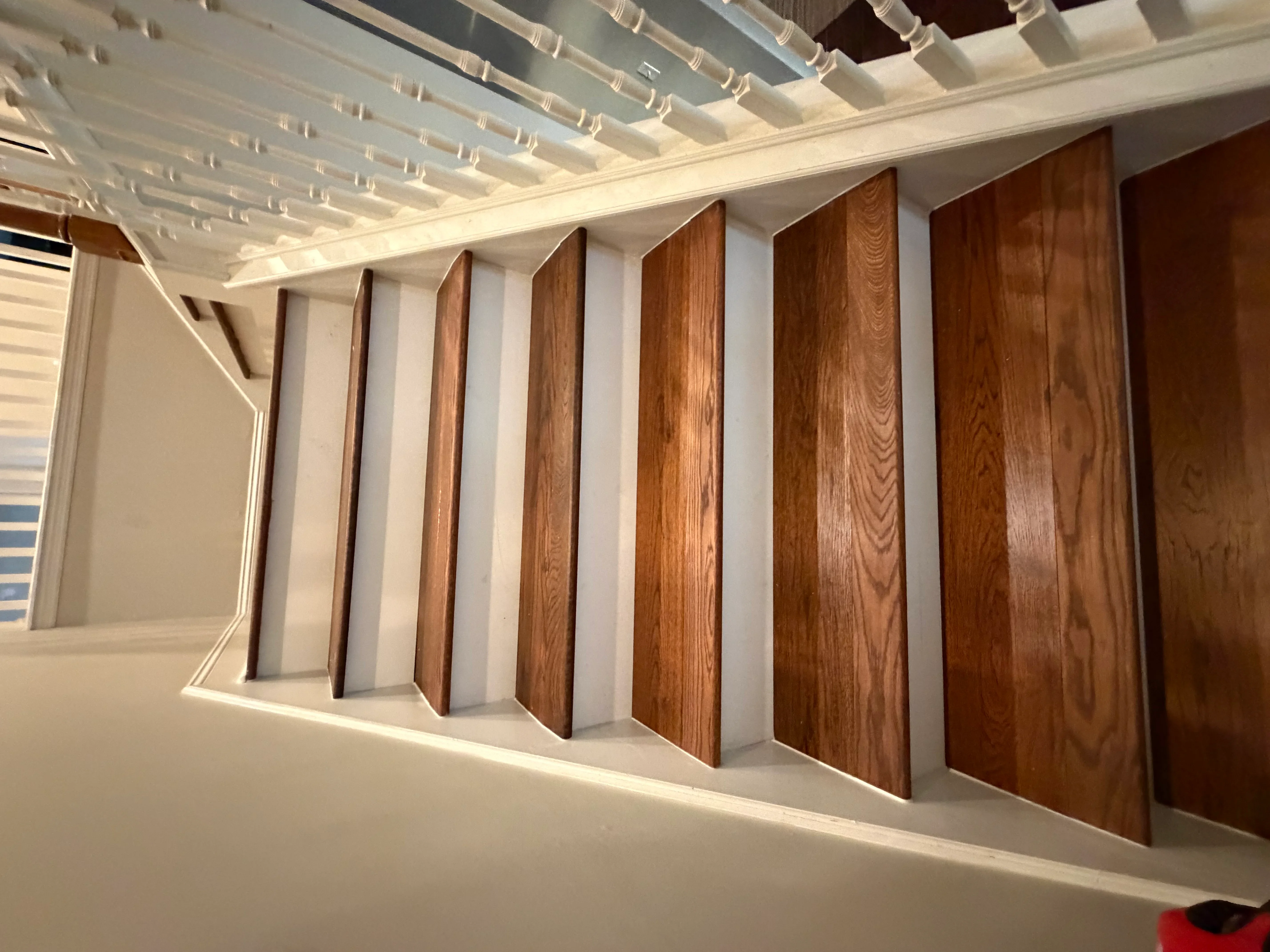 Wood flooring samples in various stains mounted on white wall with overhead lighting