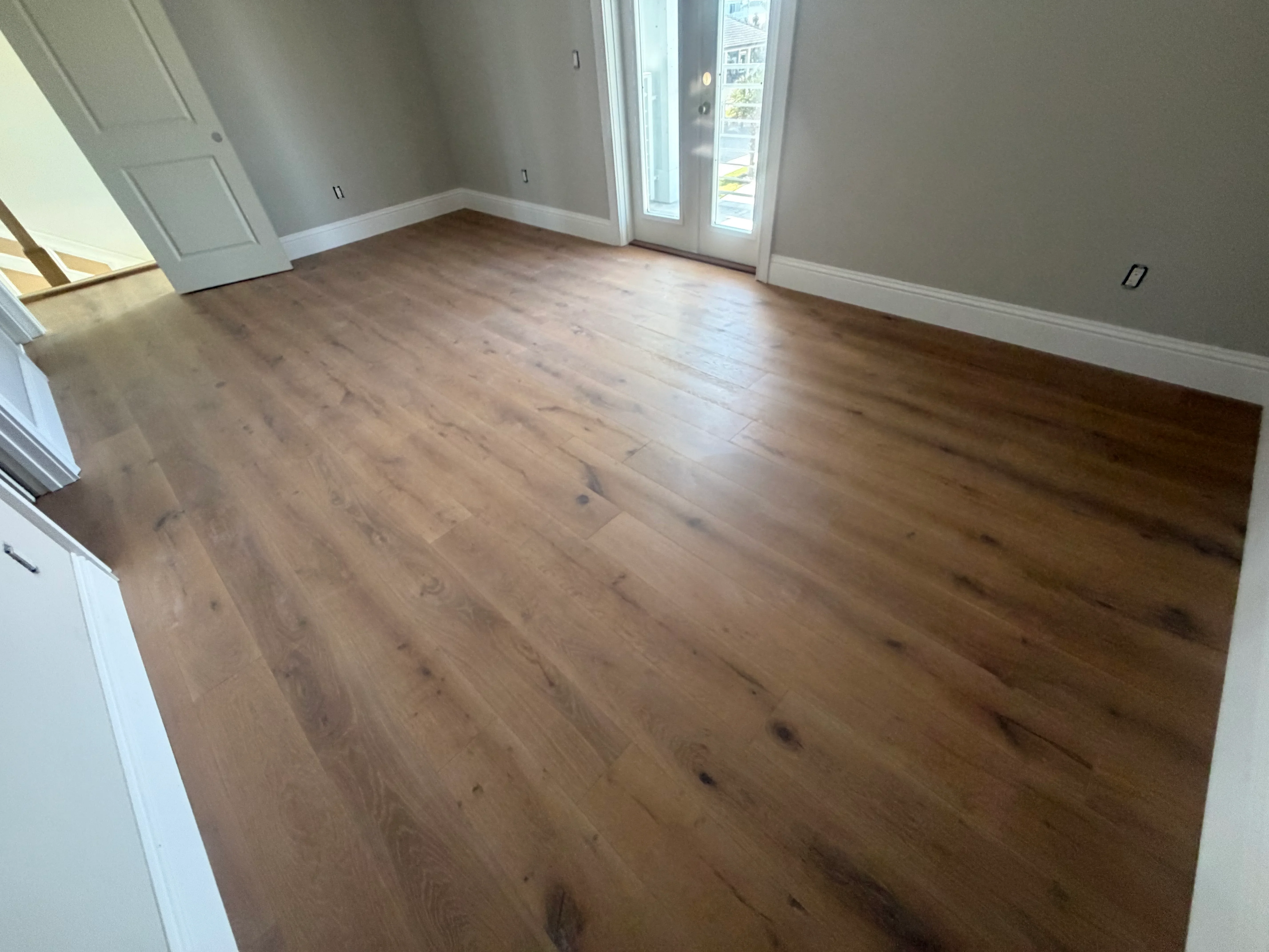 Luxury vinyl plank flooring in warm wood tone installed in open living space with white trim