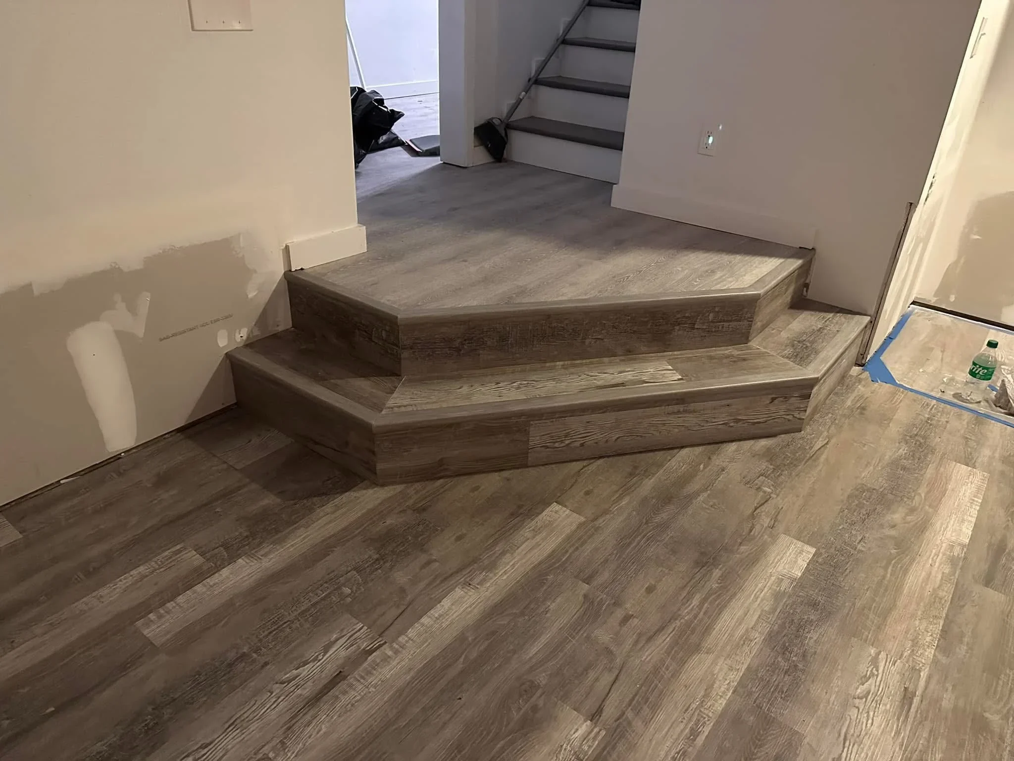 Gray wood-grain luxury vinyl plank flooring with custom built platform steps and beveled edges