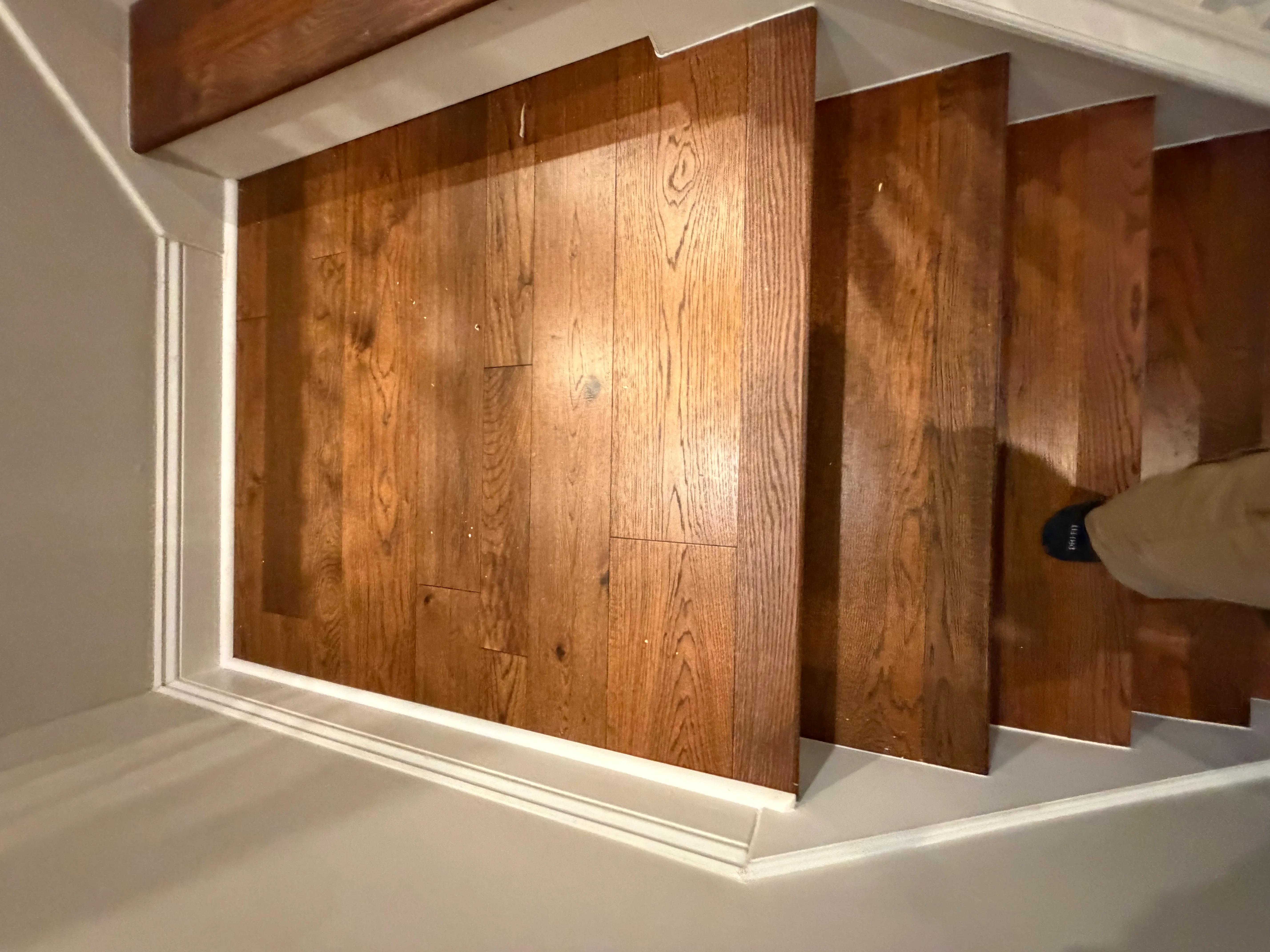Oak hardwood flooring installation with white trim and natural wood grain detail