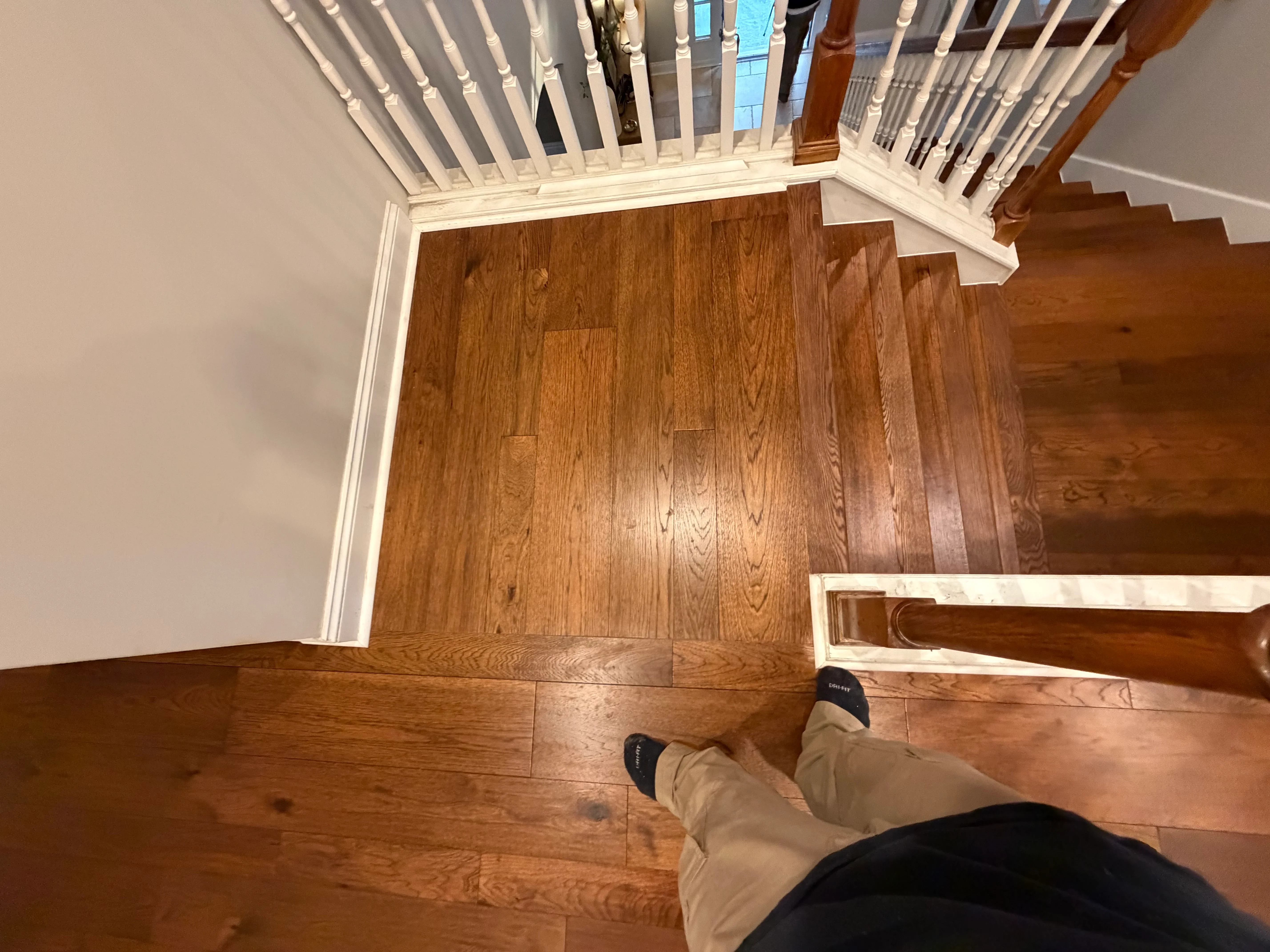 Medium-tone oak hardwood flooring with white trim and staircase integration