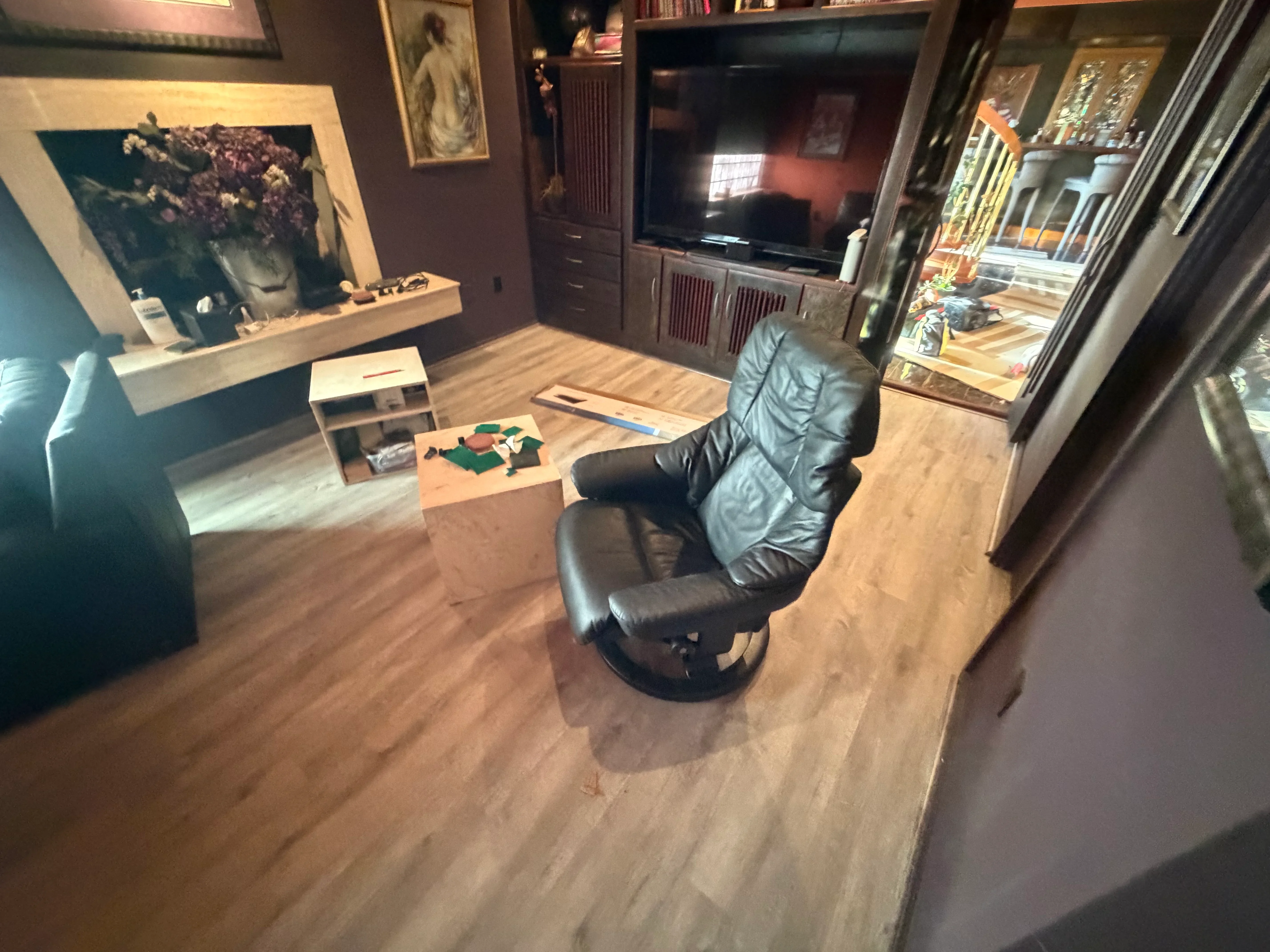 Luxury vinyl plank flooring installed in entertainment room with built-in cabinetry and shelving